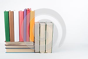 Book stack, hardback colorful books on wooden table, white background. Back to school. Copy space for text. Education