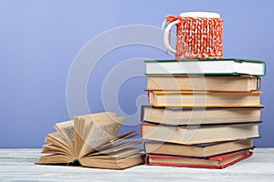 Book stacking. Open book, hardback books on wooden table and blue background. Back to school. Copy space for text.