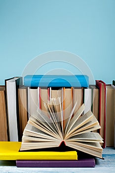 Book stacking. Open book, hardback books on wooden table and blue background. Back to school. Copy space for text