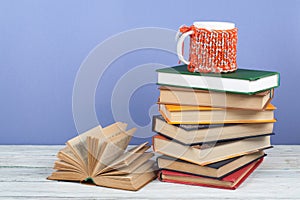 Book stacking. Open book, hardback books on wooden table and blue background. Back to school. Copy space for text