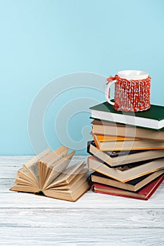 Book stacking. Open book, hardback books on wooden table and blue background. Back to school. Copy space for text.