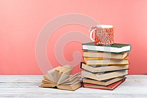Book stacking. Open book, hardback books on wooden table and pink background. Back to school. Copy space for text