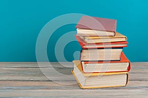 Book stacking. Open hardback books on wooden table and blue background. Back to school. Copy space for ad text