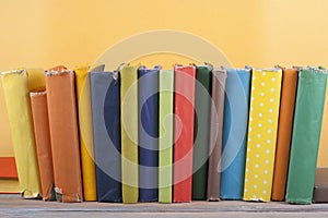 Book stacking. Open hardback books on wooden table and yellow background. Back to school. Copy space for ad text