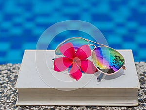 Book and sunglasses, blue water background