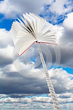 Book tied on rope soars into grey clouds