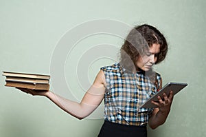 Book vs digital tablet. A woman makes a choice between books in one of her hands and digital tablet in the other