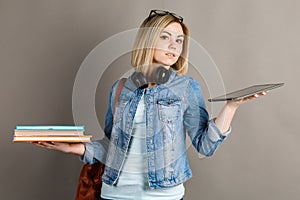 Book vs. e-book. Girl student holding a traditional textbook and