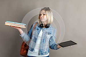 Book vs. e-book. Girl student holding a traditional textbook and