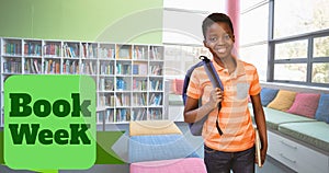 Book week text over portrait of smiling african american elementary boy standing in library