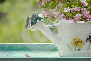 Book on the white vintage table with vase and sunglasses on green grass on sunny summer day, soft focus. Lawn with spring flowers