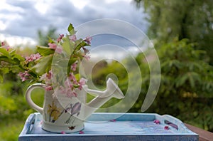 Book on the white vintage table with vase and sunglasses on green grass on sunny summer day, soft focus. Lawn with spring flowers