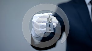 Booked word on keychain in receptionist hand, luxury hotel services, closeup