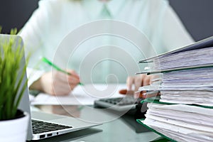 Bookkeeper or financial inspector making report, calculating or checking balance. Binders with papers closeup. Audit an photo