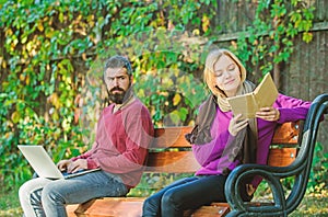 Books against computers. booklover in park. bearded man and woman on bench in park. spring weekend relax. first meet of