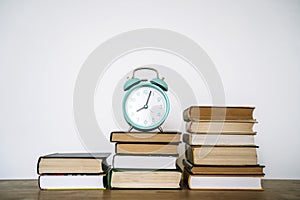 Books and alarm clock on a desk in a school or university classroom. Education, study concept background