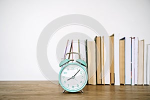 Books and alarm clock on a desk in a school or university classroom. Education, study concept background