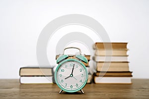 Books and alarm clock on a desk in a school or university classroom. Education, study concept background