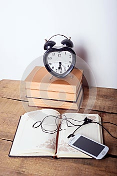 Books, alarm clock, notepad and cellphone on wooden background