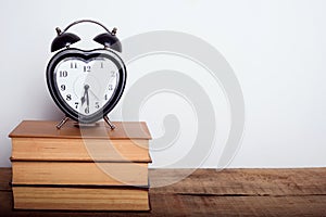 Books, alarm clock on wooden background