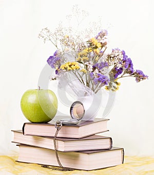 Books, antique clock and flowers