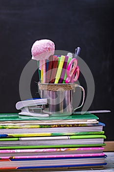 Books, apple, pens and pencils on wooden table, against the background of a chalk board. Concept for Teacher`s Day, copy space