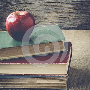 Books and apple on retro background with Instagram Style Filter