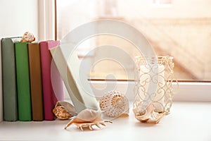Books, candle and seashells on windowsill photo
