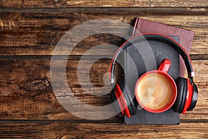 Books, coffee and headphones on wooden table. Space for text