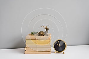 Books in craft covers on a white shelf, souvenir deer and table clock