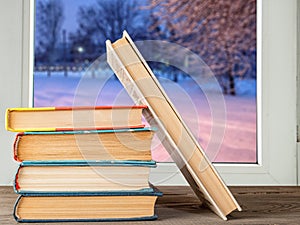 Books on the desk against the window with a winter landscape
