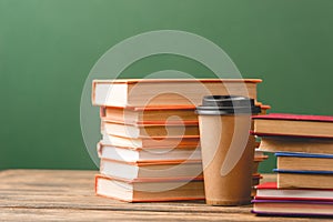 Books and disposable cup on wooden surface