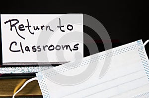 Books, Face Mask, and Return to Classrooms note with black background photo