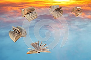 Books fly over sunset clouds