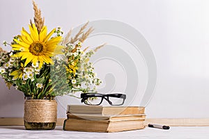 Books, glasses, markers and a bouquet of flowers in a vase on white board background. Concept for teachers day and first September