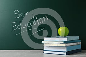 Books on grey table near chalkboard with phrase