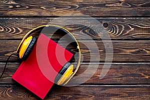 Books with headphones for listening to audiobook on wooden background top view copy space