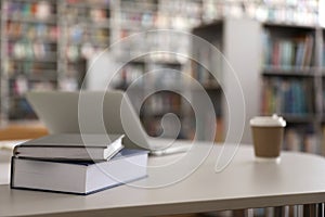 Books, laptop and drink in library