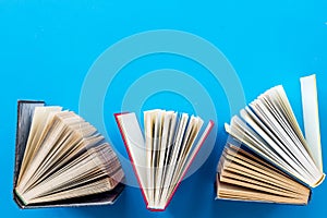 Books on library desk on blue background top view space for text