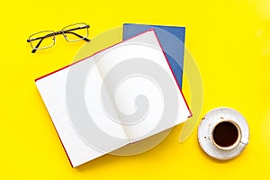 Books on library desk for reading, coffee, glasses on yellow background top view mockup