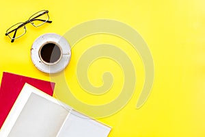 Books on library desk for reading, coffee, glasses on yellow background top view mockup