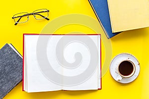 Books on library desk for reading, coffee, glasses on yellow background top view mockup