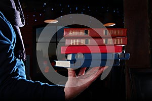 Books in a man`s hand. Unrecognizable photo. Different volumes of books. Photo on a black background. Copy of the space