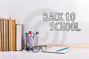 Books, markers, notebook, pencil and glasses on the table against the background of a white board. Copy space