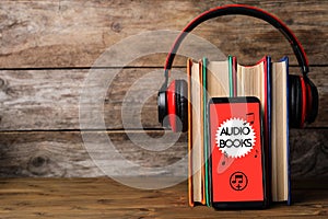 Books with modern headphones and smartphone on table. Space for text photo