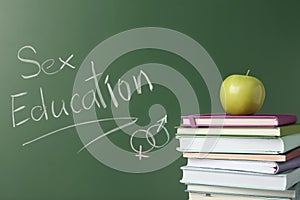 Books near chalkboard with phrase `Sex education`