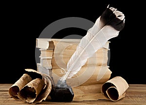 Books, old paper and feather in an inkwell isolated on a black background