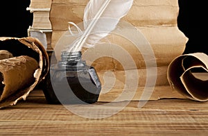 Books, old paper and feather in an inkwell isolated on a black background