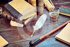 Books, paper and feather for writing in ink. Table with retro writing utensils