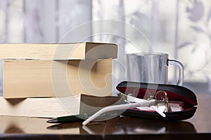 Books, pen, drink and glasses over a wood table close-up